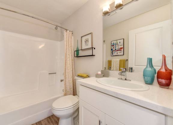 A white bathroom with a toilet, sink, and shower.