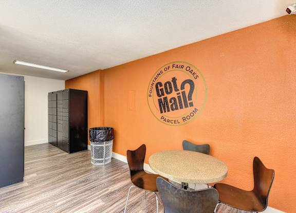 Parcel Room with Hardwood Inspired Floor, Short Round Tables, Chairs, Orange Wall with at Fountains of Fair Oaks, California