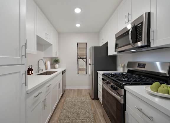 A modern kitchen with white cabinets and stainless steel appliances.