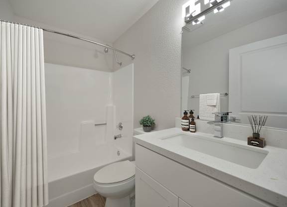 A white bathroom with a toilet, sink, and shower.