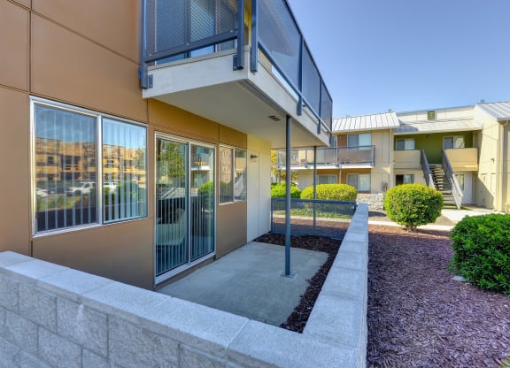 Private Patio with Porch, Wood Chip Floor, Bushes, and Open Blind Windows at Addison Ranch Apartments, California