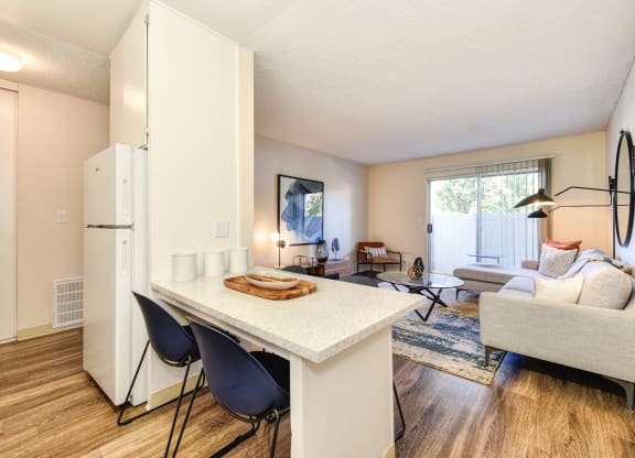 Kitchen with View of Living Room, Hardwood Inspired Floor, White Table and Blue Chairs at Renaissance Park Apartments, California, 95618