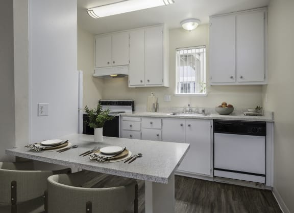 a kitchen with white cabinets and a table and chairs at Renaissance Park Apartments, California