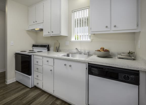 a kitchen with white cabinets and a sink and a dishwasher at Renaissance Park Apartments, California
