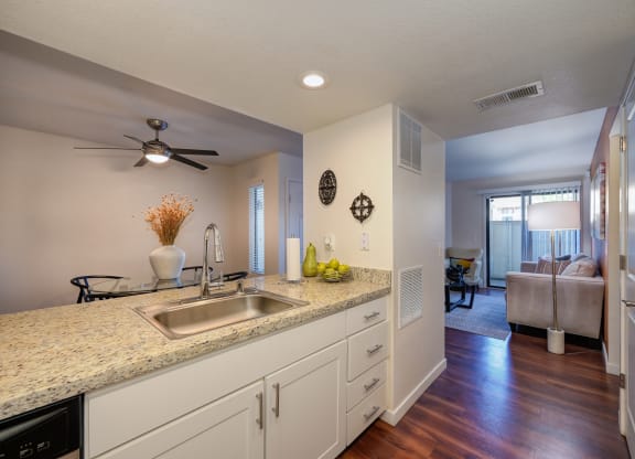 Model kitchen with hard wood inspired flooring, white counters, ceiling fan in dining area and views of the living room at Rocklin Manor  Apartments, Rocklin  , CA