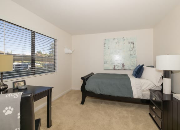 a bedroom with a bed and a desk and a window at Rocklin Manor  Apartments, California, 95677