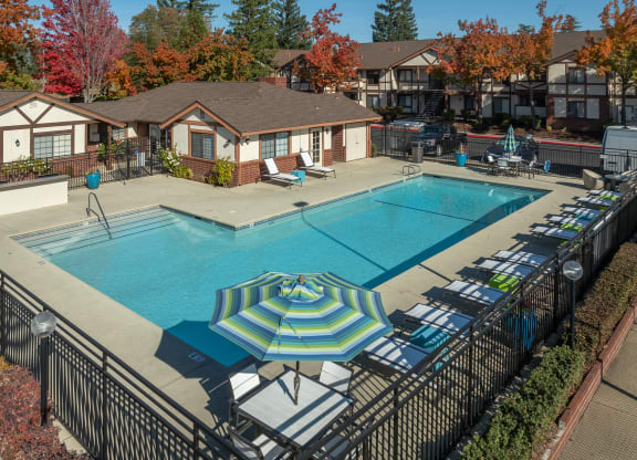 a swimming pool with umbrellas and lounge chairs around it at Rocklin Manor  Apartments, Rocklin  ,California, 95677