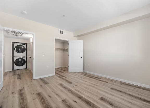 a living room with white walls and wood floors and a washer and dryer