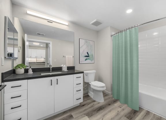 a bathroom with white cabinets and a green shower curtain