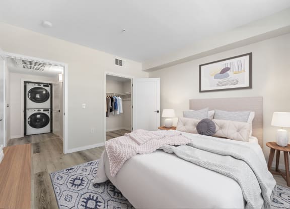 a bedroom with a bed and a closet with a washer and dryer