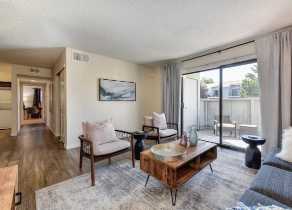 Living with Sliding Patio Doors,  Hardwood Inspired Floor, Gray/White Rug, Gray Sofa and Round Mirror at Silverstone Apartments, California, 95618