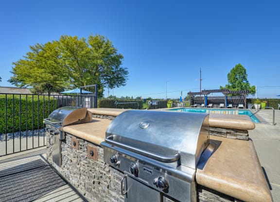 BBQ Picnic Area with Grills and View of Lounge Chairs and Pool at Silverstone Apartments, Davis, California