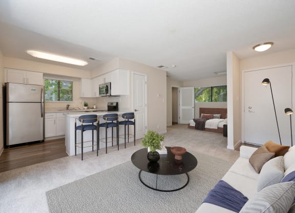 a living room with a couch and a table in front of a kitchen at Silverstone Apartments, Davis