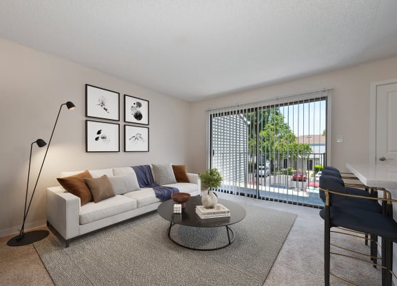 an open living room with a couch and a coffee table and a balcony at Silverstone Apartments, Davis, California