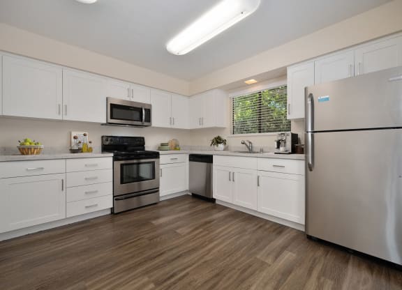 a kitchen with white cabinets and stainless steel appliances in the townhome floorplan at Silverstone Apartments, Davis, CA, 95618