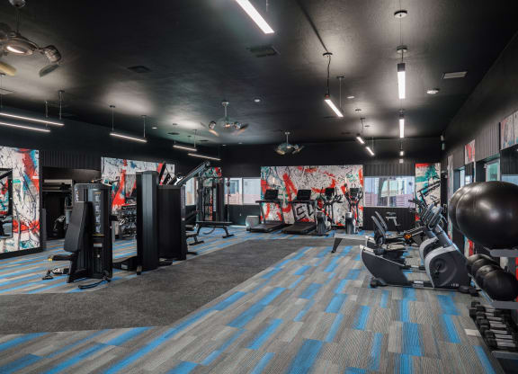 a fitness room with weights and other exercise equipment and a wall of graffiti