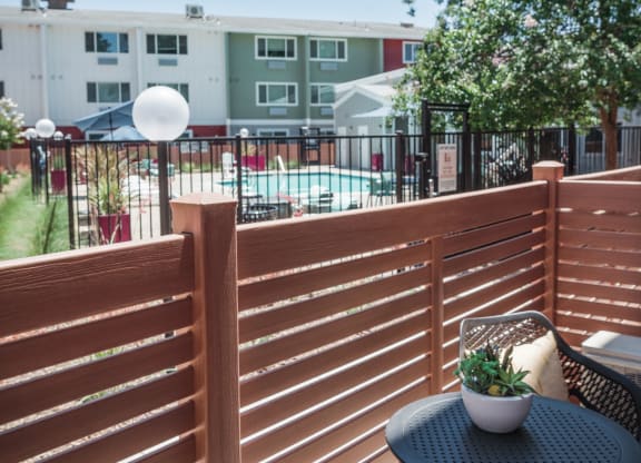 a patio with two chairs and a table on a balcony  overlooking the pool area at Track 281 Apartments, Sacramento, 95811