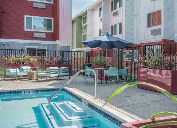our apartments have a pool and a patio with chairs and an umbrella