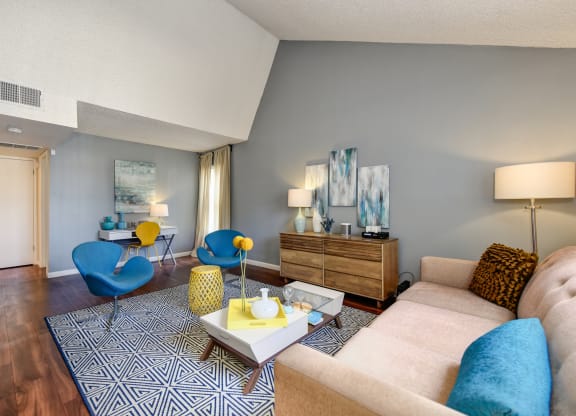 Model home with vaulted ceilings, hardwood inspired flooring and blue accents with the chairs and couch pillows at Vineyard Terrace Apartments, California 94558