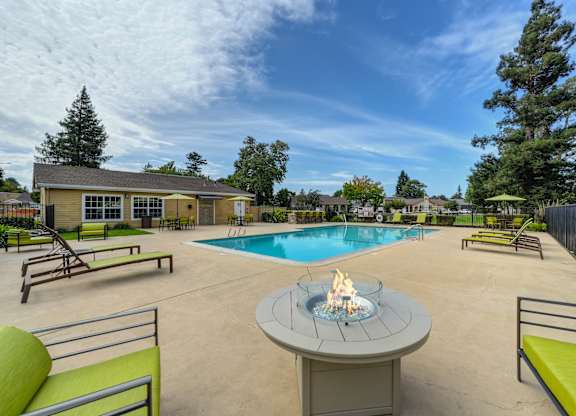 A poolside area with a fire pit in the middle of a concrete patio at Vineyard Terrace Apartments, California