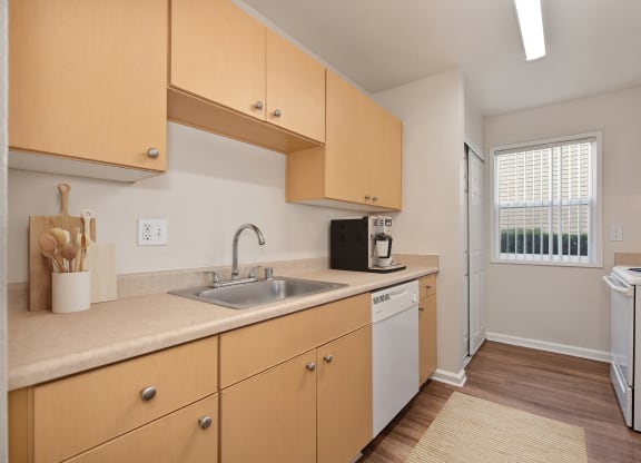 a kitchen with wooden cabinets and a sink and a window at Vineyard Terrace Apartments, California, 94558