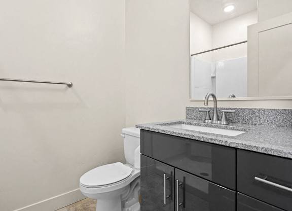 A bathroom with a toilet, sink, and mirror.