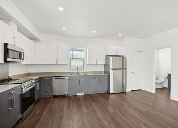 A modern kitchen with wooden floors and stainless steel appliances.