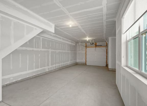the unfinished basement of a house with white walls and a garage door