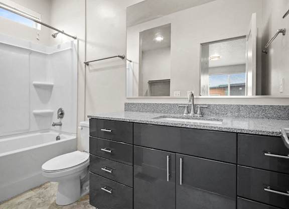 A modern bathroom with a white toilet and a black vanity.