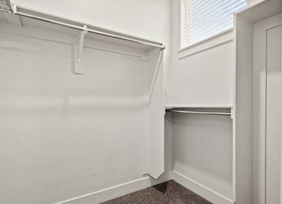 A white closet with a shelf and a white door.
