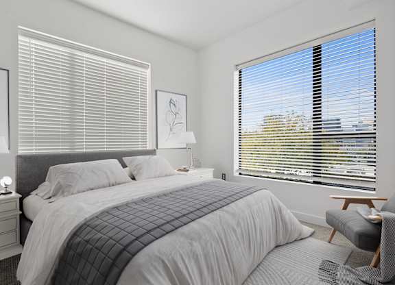 a bedroom with a large bed and two windows