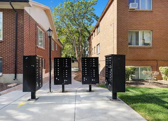 Four black parking meters are lined up on a sidewalk.