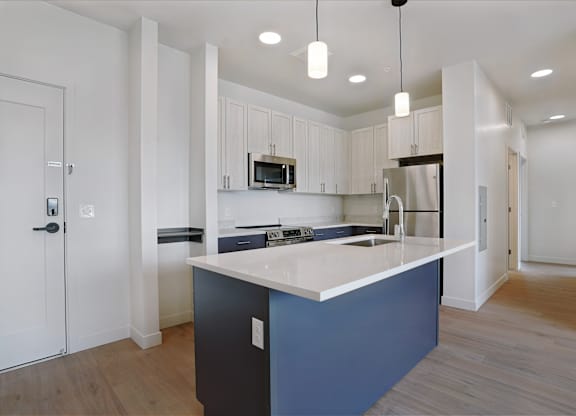 A kitchen with a white countertop and blue cabinetry.