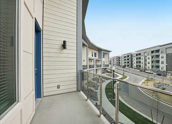 A balcony with a blue door and a glass railing.