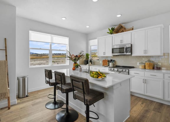 a white kitchen with a large counter and chairs