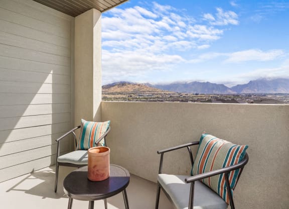 a balcony with two chairs and a table with a view of the mountains