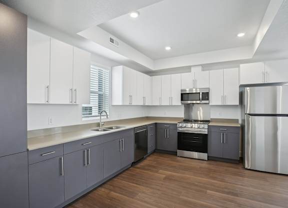 A modern kitchen with wooden floors and stainless steel appliances.