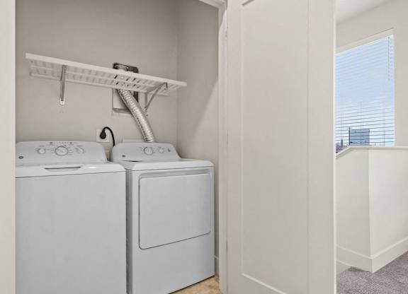 Two white front loading washing machines in a small laundry room.