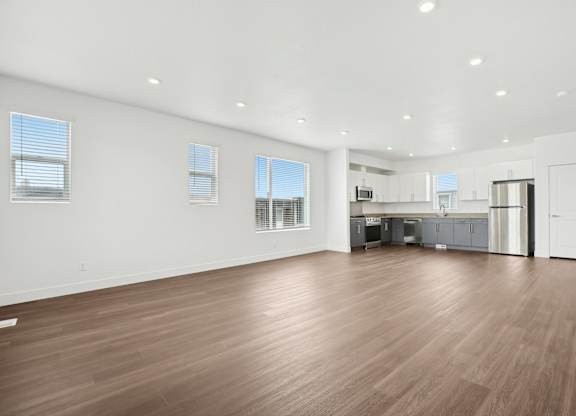 A spacious room with wooden flooring and white walls.