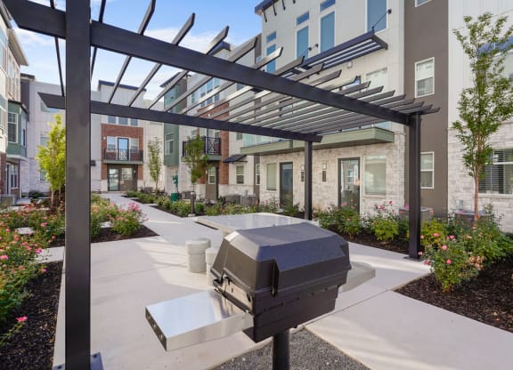 an outdoor patio with a grill in front of an apartment building