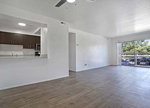 A spacious room with wooden flooring and a ceiling fan.