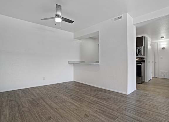 A room with a ceiling fan and wooden flooring.