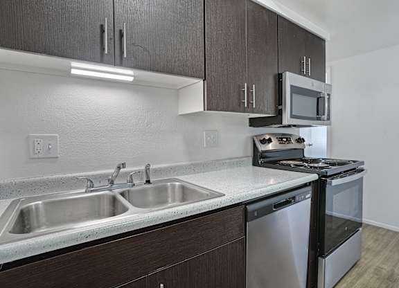 A kitchen with a stainless steel sink and black cabinets.
