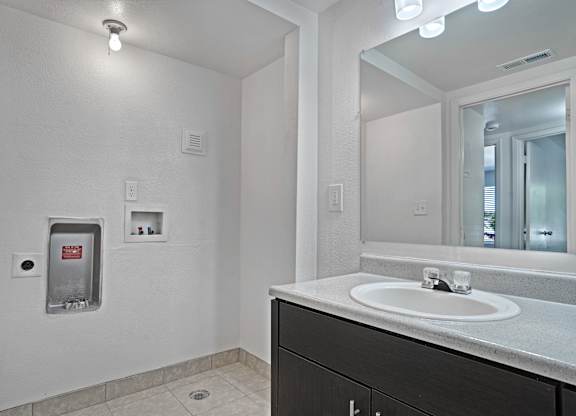 A bathroom with a sink, mirror, and a water fountain.