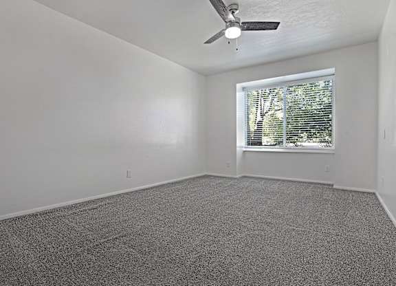 A room with a ceiling fan and a window with blinds.