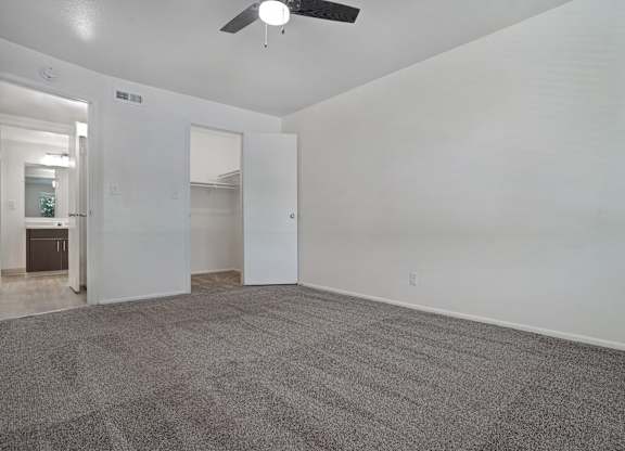 A room with a ceiling fan and carpeted floor.
