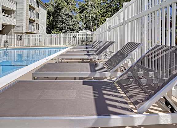 A row of sun loungers are on the edge of a pool.