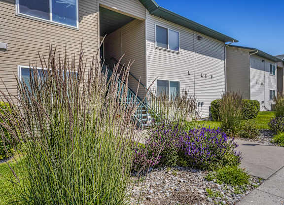 A beige apartment building with a green lawn in front.