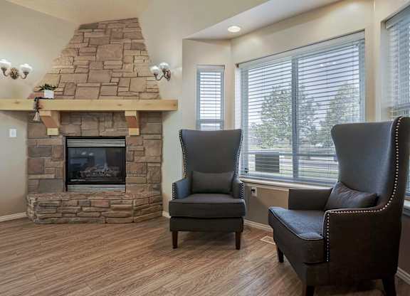 A living room with a stone fireplace and two leather chairs.