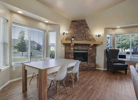 A dining room with a stone fireplace and a table set for four.